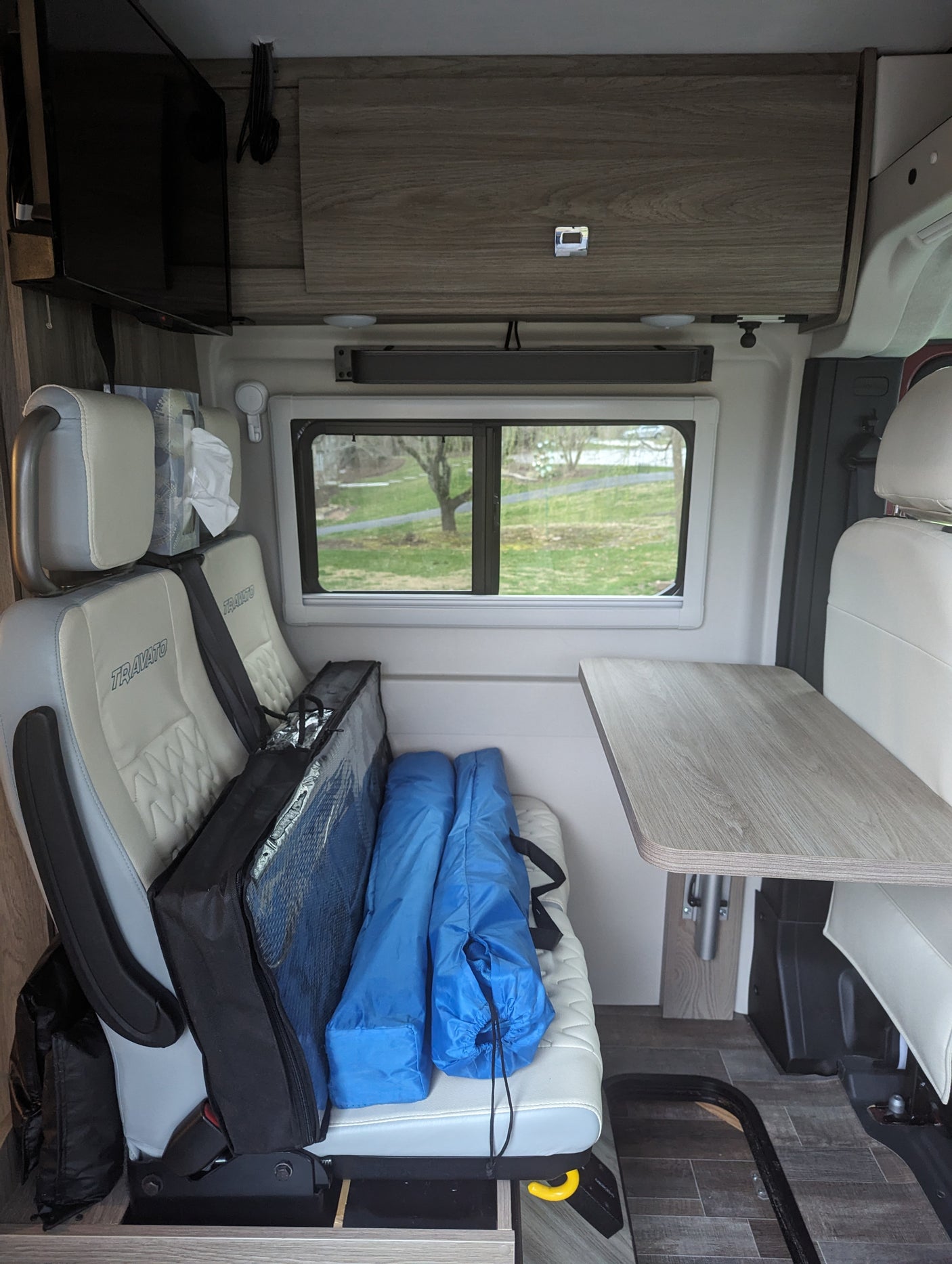 This RV rental interior features swiveling front seats, a compact dining table, and smart storage for a camper van adventure.