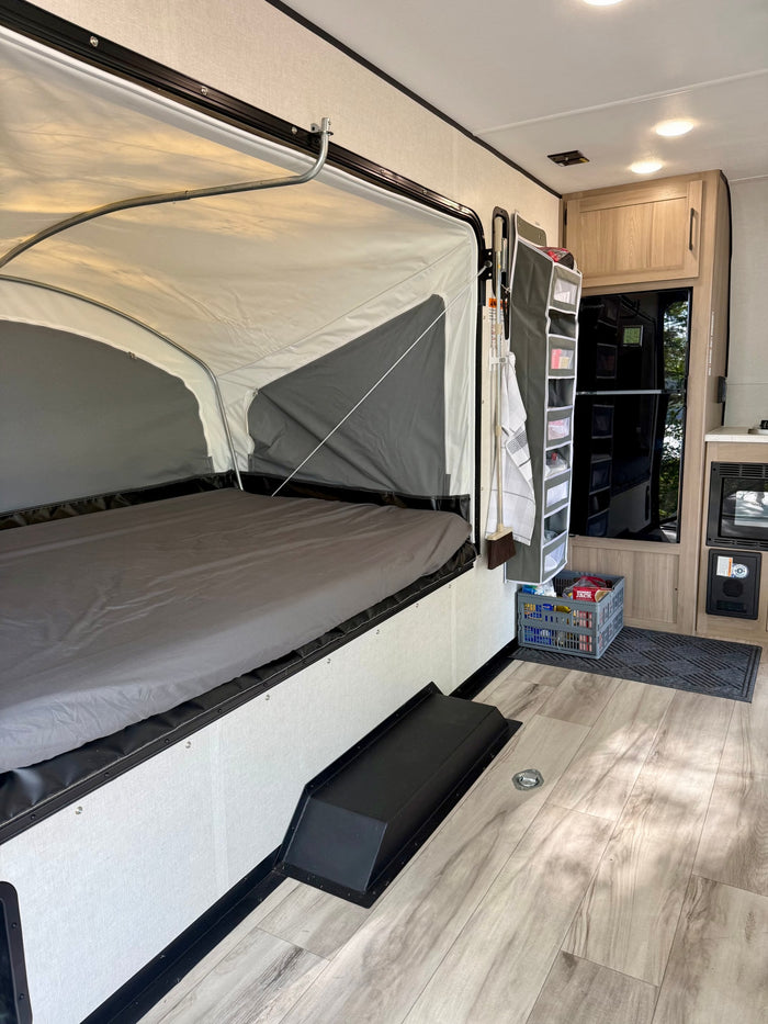 with a lake visible in the background.|RV rental interior: A compact living space with a pop-out bed