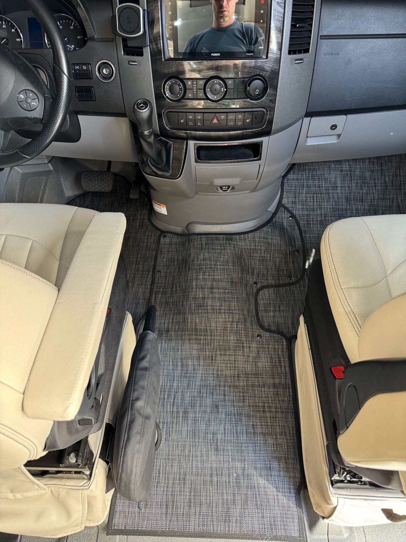 Spacious RV rental cockpit featuring light seats, a modern dashboard, and custom-fit grey floor mat.