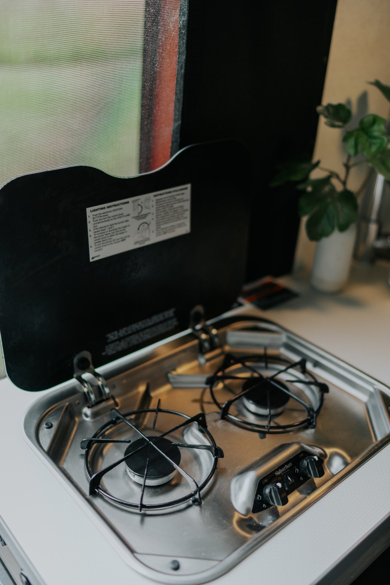 RV rental kitchen showing a two-burner Suburban gas stove with lighting instructions on the lid.