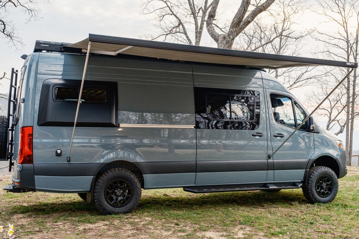 Gray Sprinter camper van with an extended awning, off-road tires, and rear ladder, ideal for your next RV rental adventure. — photo 2