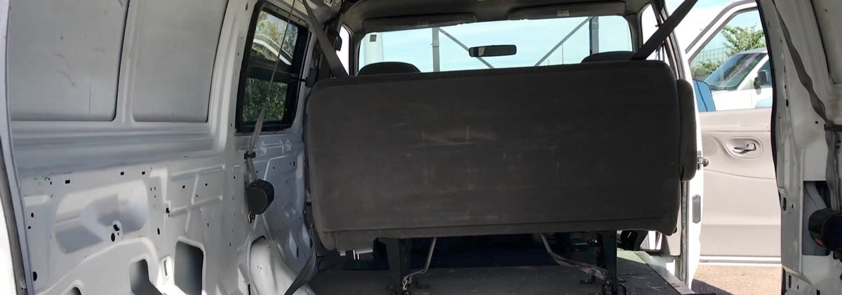 View of a white van's interior, showing bare walls and a dark bench seat, ideal for an RV rental. — photo 2
