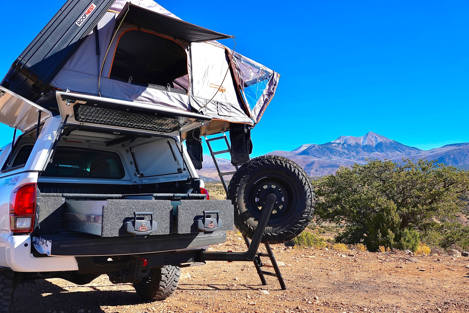 Overland ready: white truck with Roofnest rooftop tent, ARB drawer system & spare tire carrier. Consider this for RV rental.