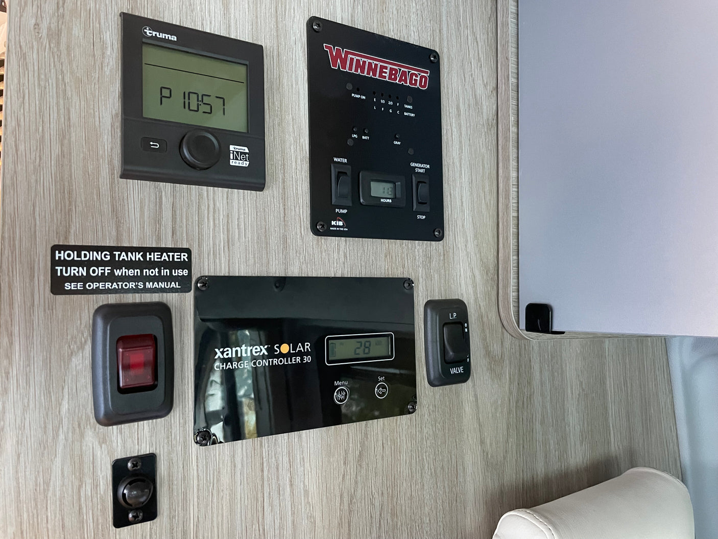 RV rental wall panel with controls for Truma heating, Winnebago systems (tanks, gen), Xantrex solar, and tank heater.