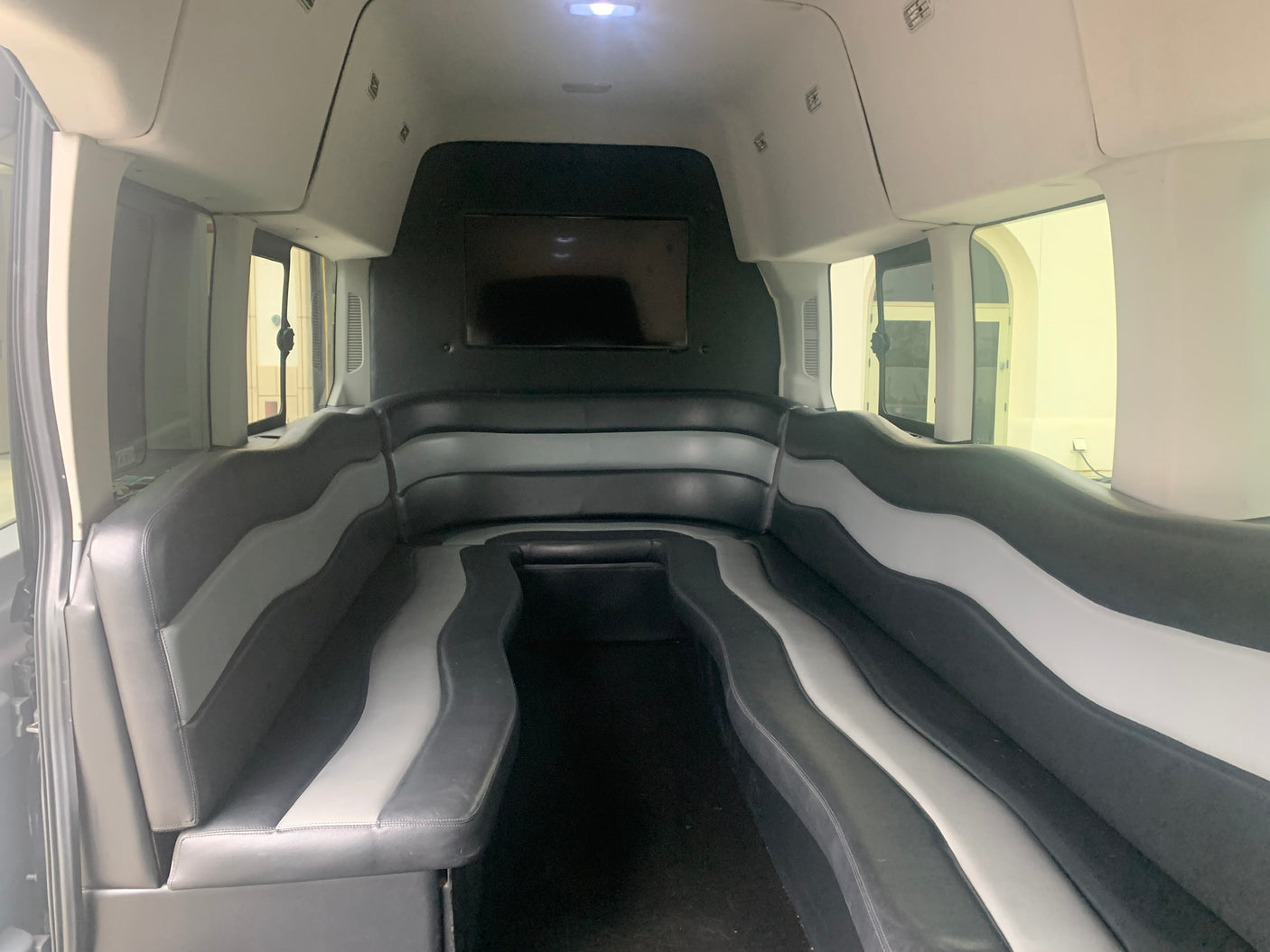 Spacious RV rental interior with black and gray luxury seating and a TV, perfect for group travel.