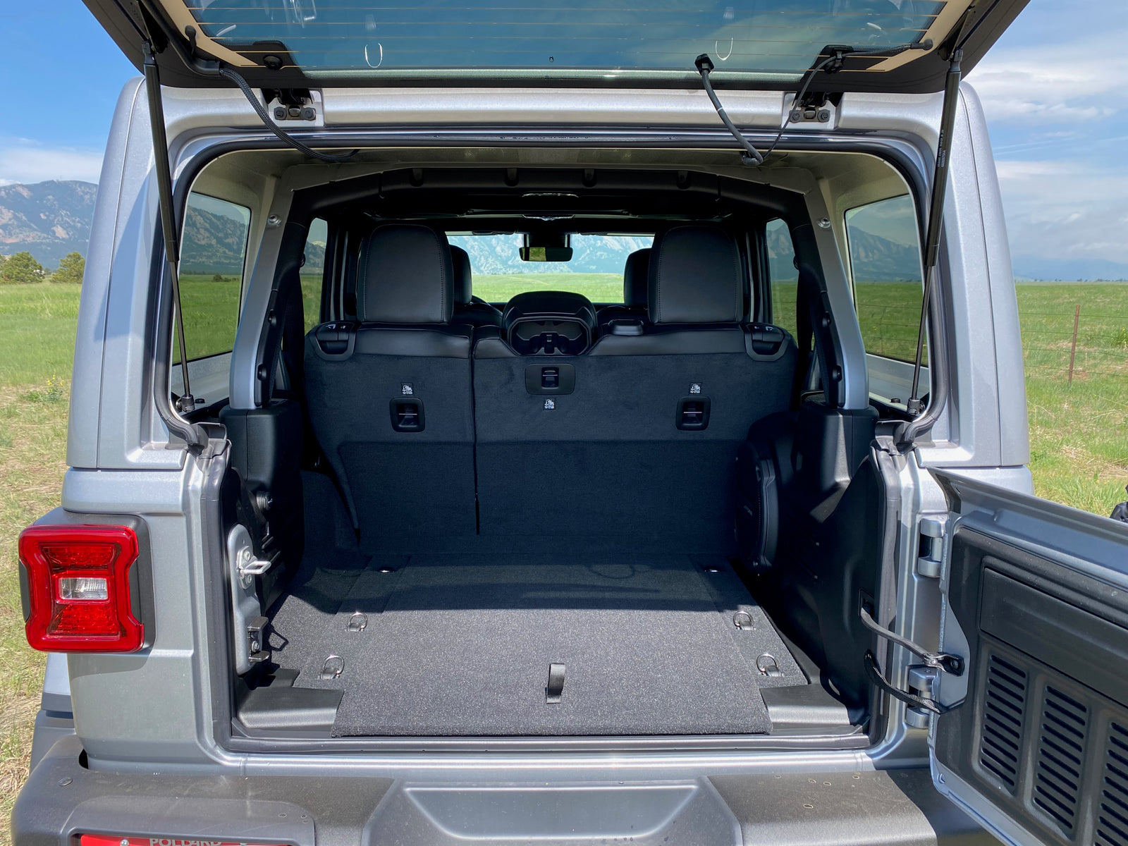 Rear interior of a silver Jeep SUV with tailgate open, showing ample cargo space for your next adventure or rv rental.