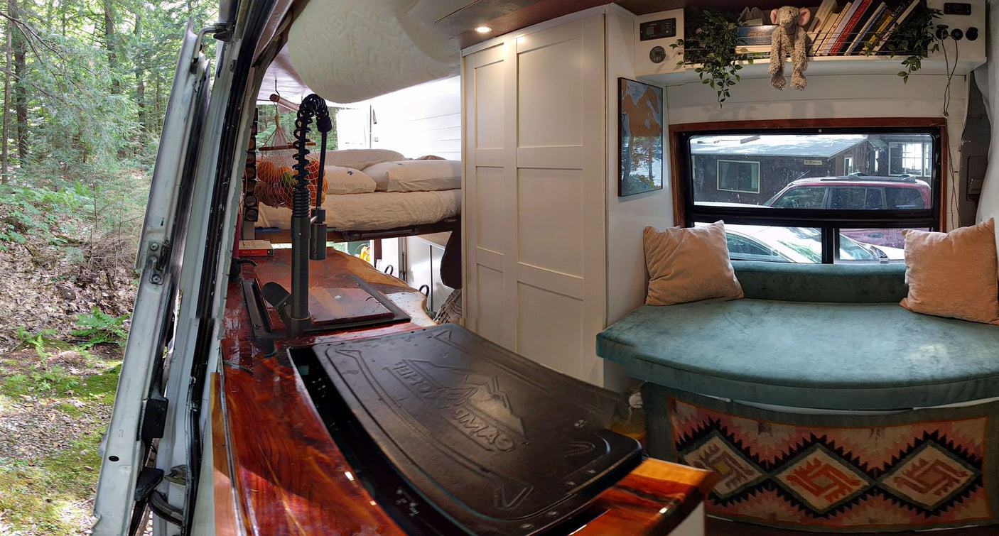Modern rv rental interior: kitchen, raised bed, and curved lounge with window views.