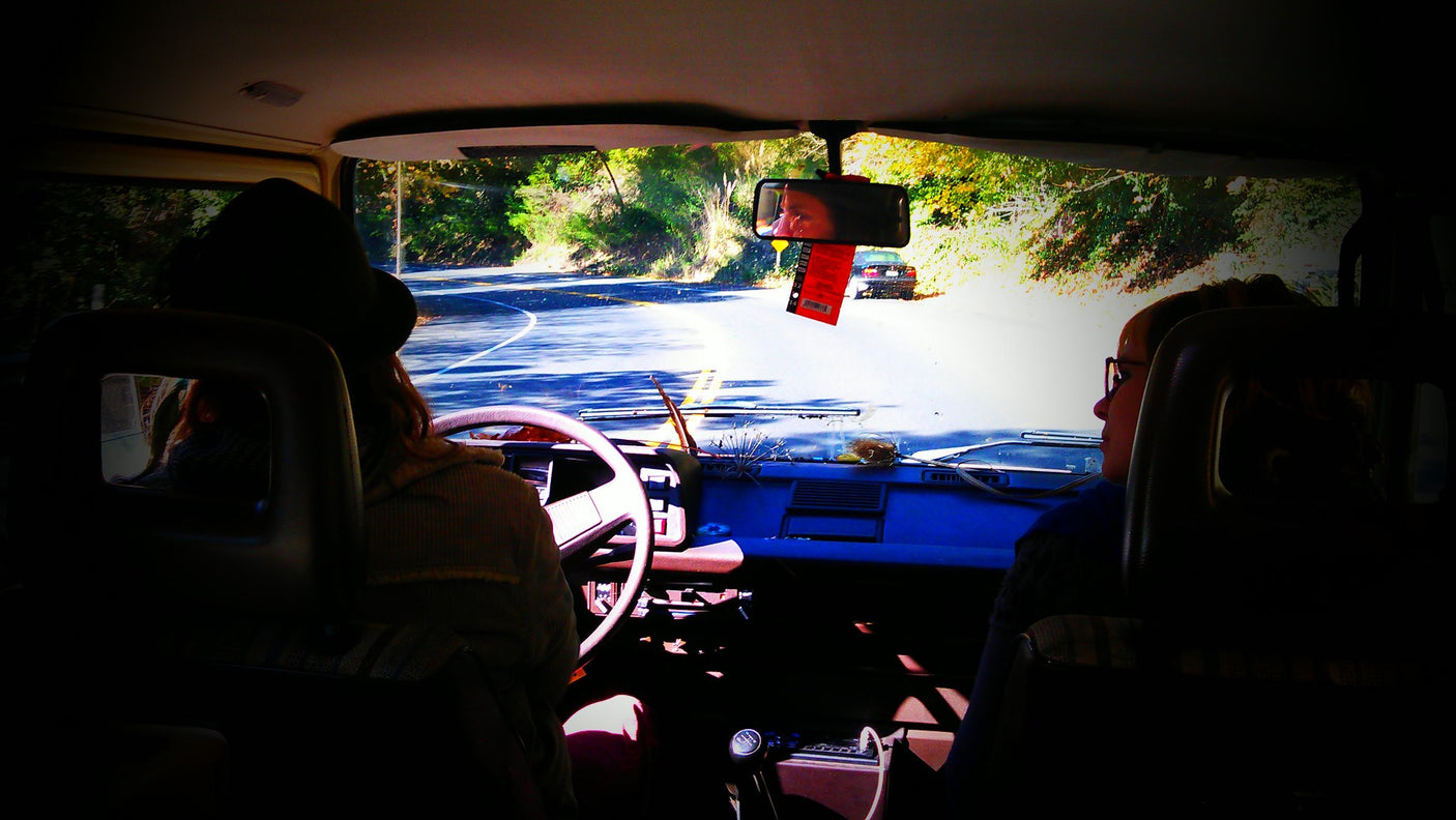 Inside an RV rental on a scenic road trip. Driver & passenger enjoy the view of the winding road ahead.
