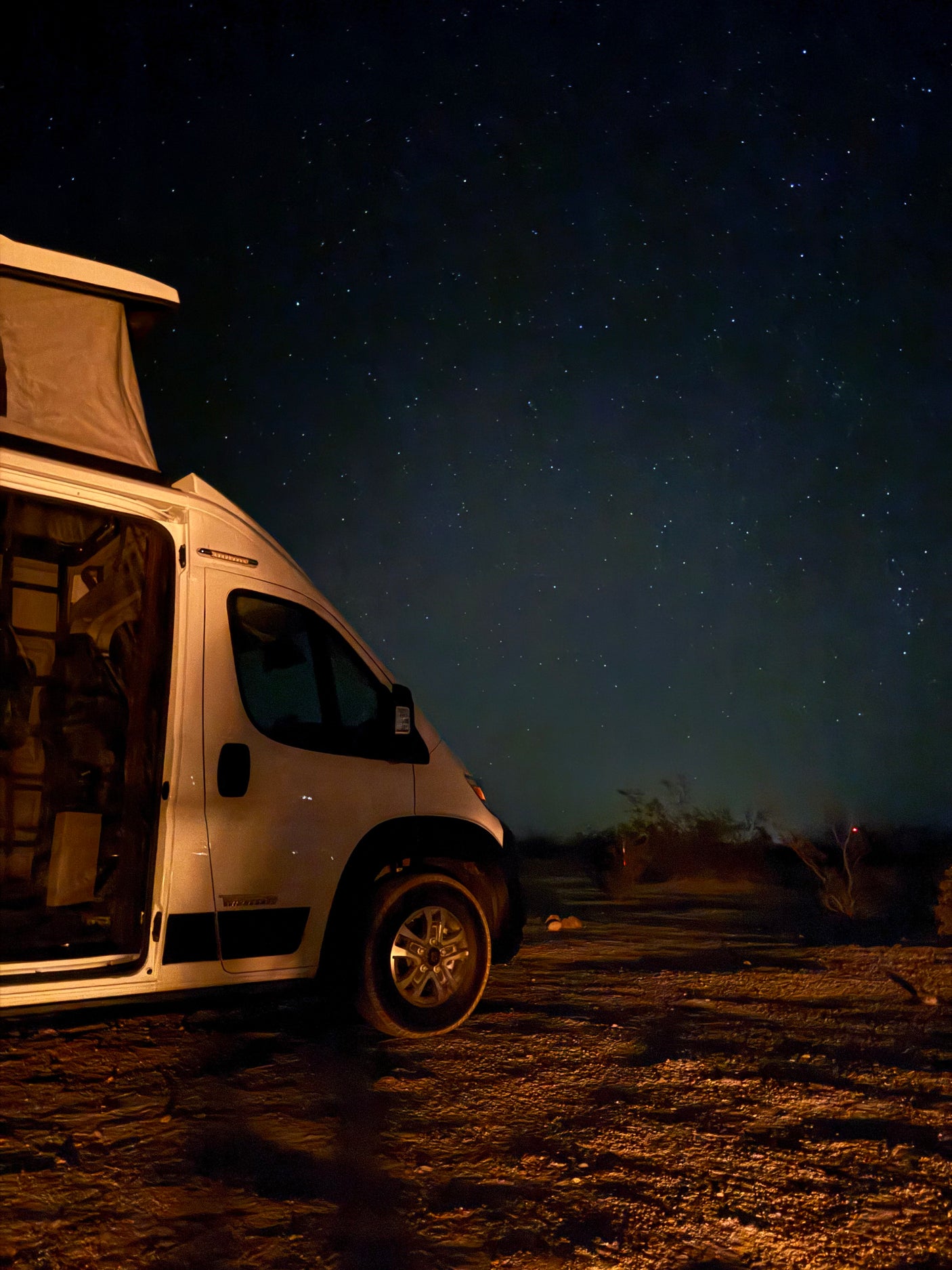 and mesh screen offering desert mountain views.|White Winnebago Solis RV rental with pop-top tent