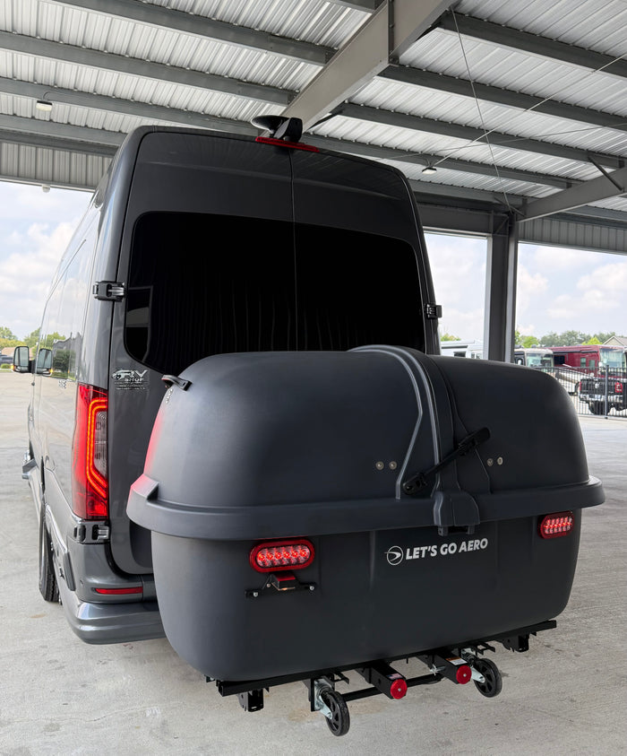 This grey RV rental van features a large "Let's Go Aero" rear cargo box, ideal for travel storage.