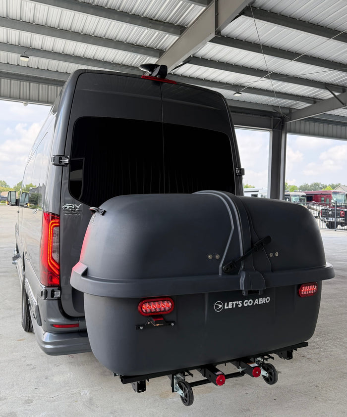 parked on a sunlit driveway with trees.|A modern gray Mercedes-Benz Sprinter rv rental parked on a concrete driveway
