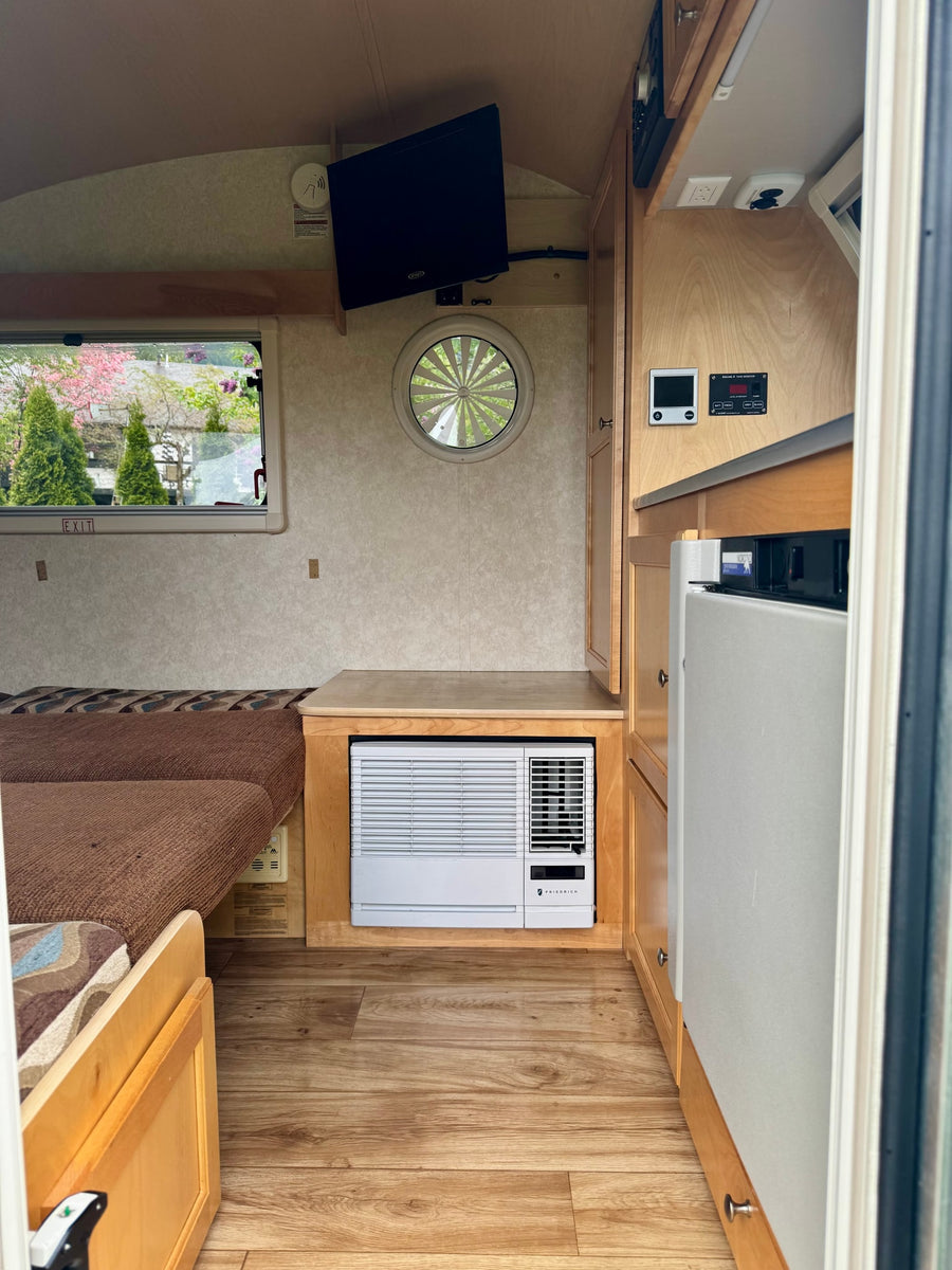 and a scenic window view.|Cozy RV rental interior featuring a comfy bed with patterned cushions