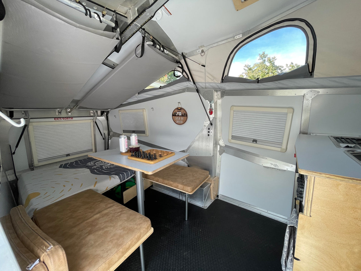 Step inside this compact pop-top RV rental, featuring a cozy bed, dinette with chessboard, and integrated kitchen area.