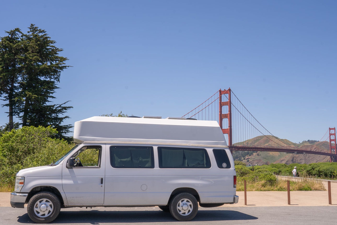 White high-top RV rental van parked near the iconic Golden Gate Bridge, ideal for scenic travels.