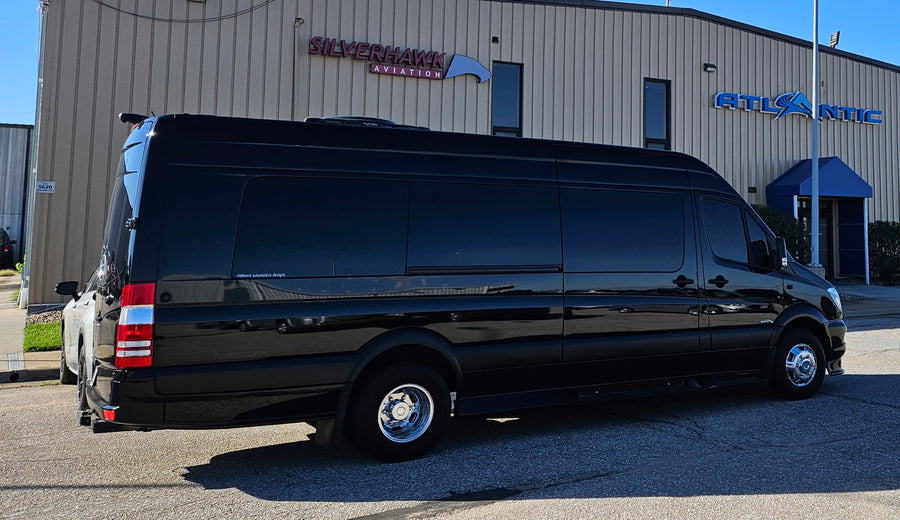 Black luxury Sprinter van, ideal for rv rental, with tinted windows & chrome wheels. Parked by Atlantic Aviation.