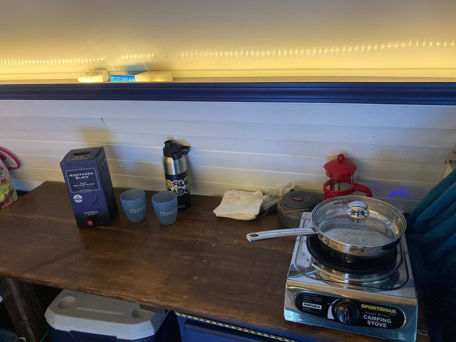RV rental cooking and dining station: Sportsman camping stove, Nighthawk wine, and coffee maker on a wooden counter.