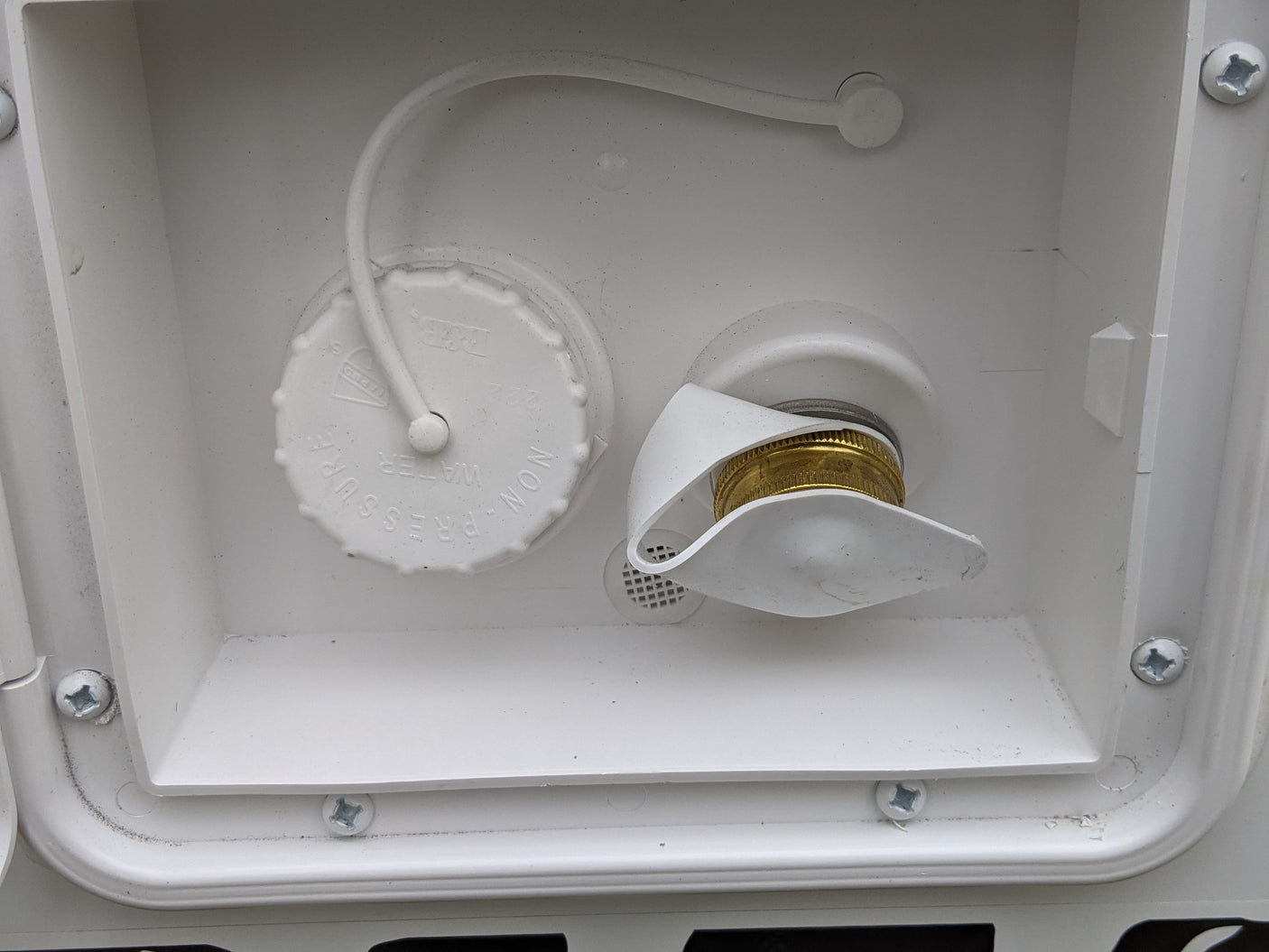 RV rental water fill and city water hookup. White compartment showing non-pressure water cap and brass hose inlet for an RV.