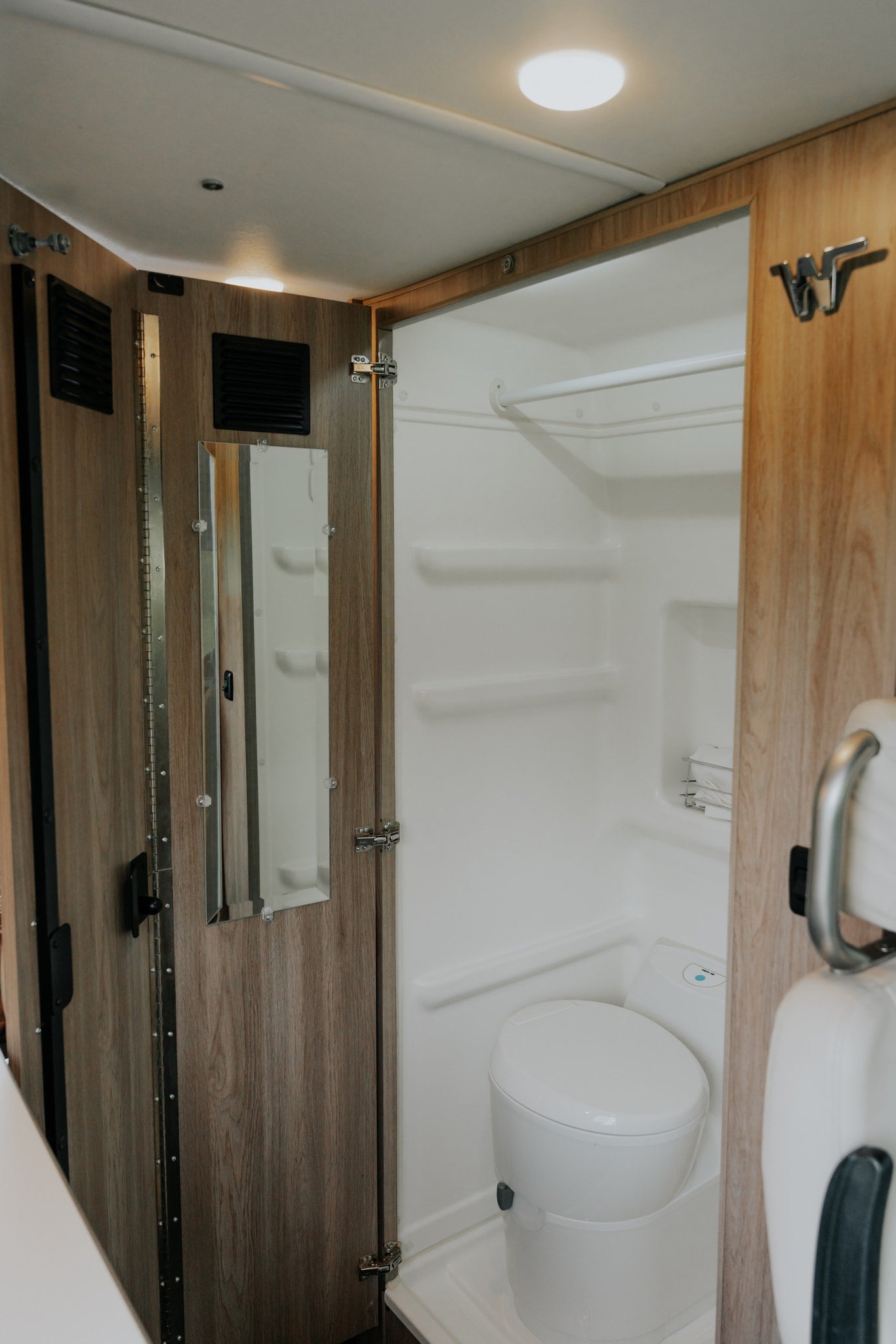 This RV rental boasts a full, compact bathroom with a shower, toilet, and built-in shelving, ensuring comfort on the go.