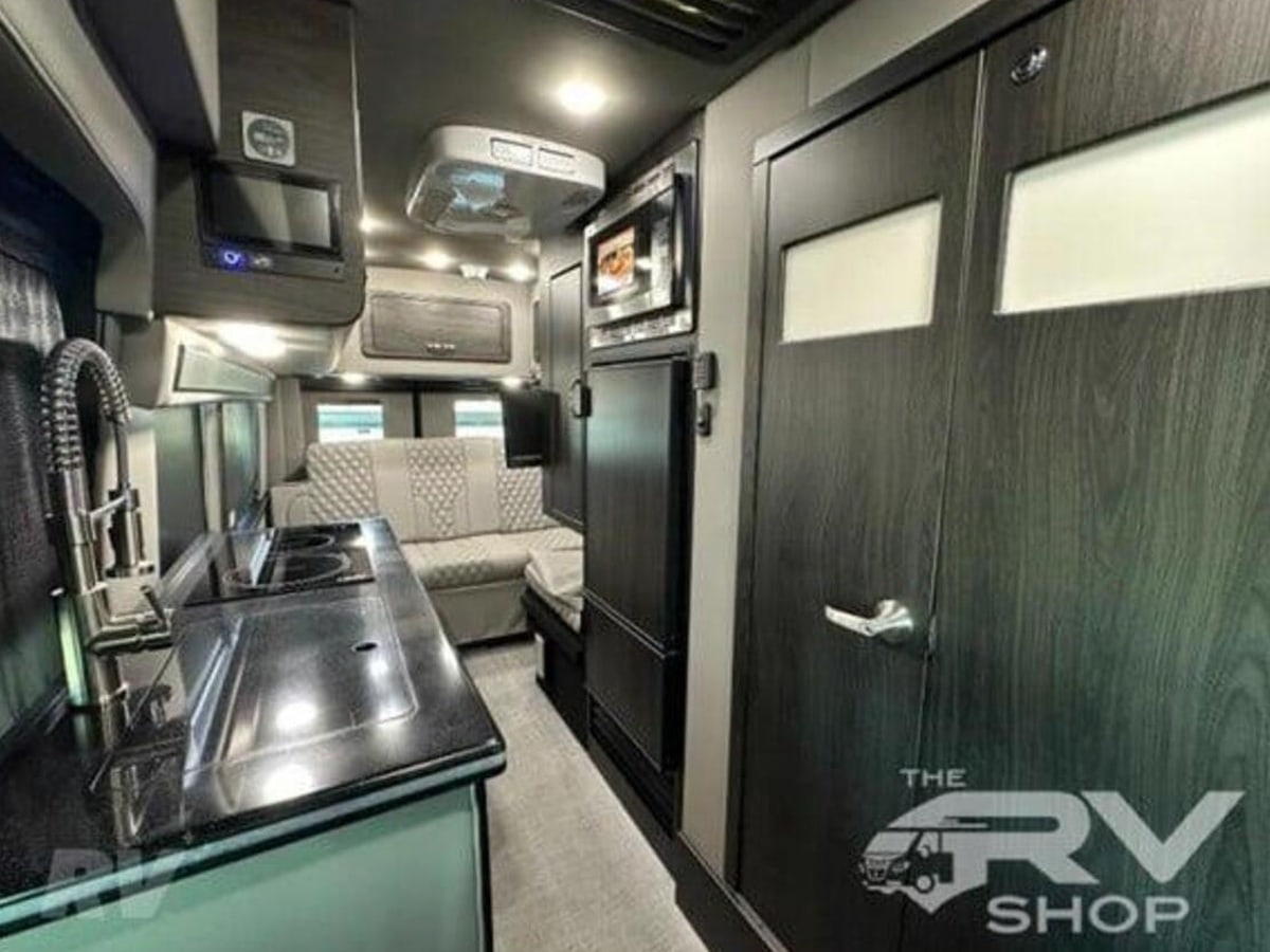 quilted bench seating and large windows for travel.|Modern RV rental interior: Light-colored — photo 12
