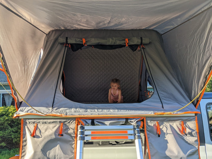 accessible by a ladder. Perfect for RV rental trips!|A white Jeep with an open rooftop tent sits on a sunny green lawn. Ready for adventure camping