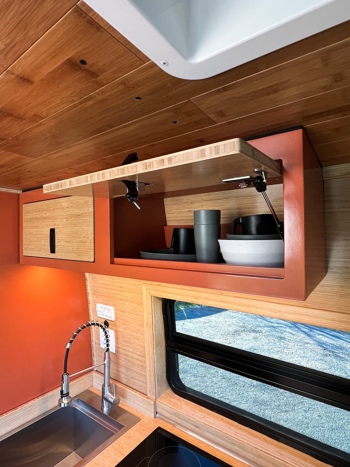 and kitchen area.|RV rental's custom van interior: wood-paneled ceiling — photo 9