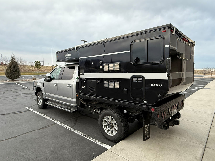 A silver truck with a black Four Wheel Campers Hawk+ pop-top truck camper, ready for your next rv rental overland adventure.
