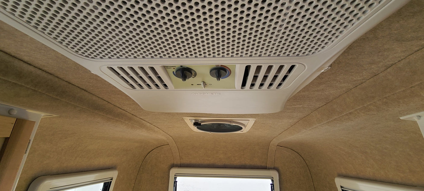 This RV rental's ceiling features a Dometic AC/heater unit, vents, and a light brown fabric lining, with windows below.