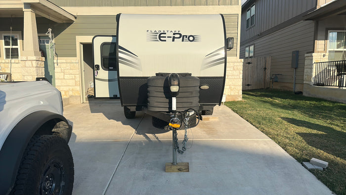 This Flagstaff E-Pro travel trailer in a driveway, ready for an rv rental, is partially obscured by a white Bronco.