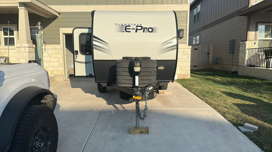 This Flagstaff E-Pro travel trailer in a driveway, ready for an rv rental, is partially obscured by a white Bronco.