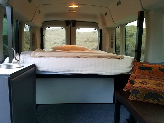 Cozy rv rental interior: comfortable bed, functional sink, and scenic outdoor views from the windows.
