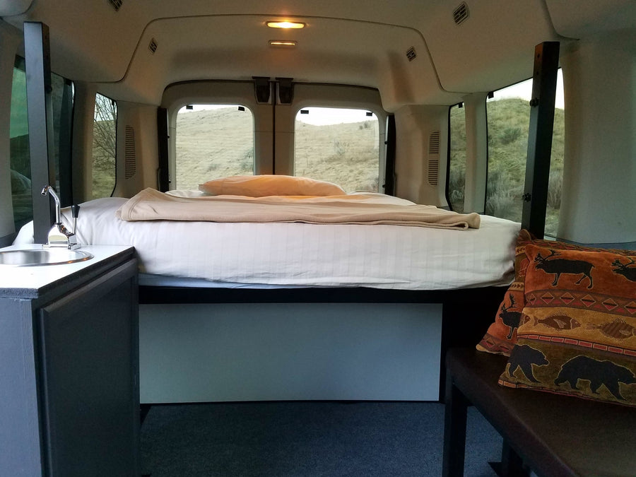 Cozy rv rental interior: comfortable bed, functional sink, and scenic outdoor views from the windows.
