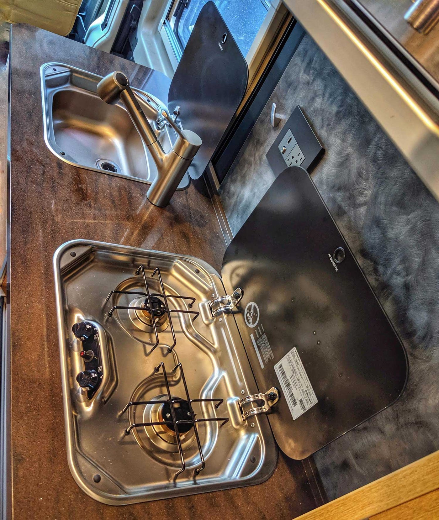 and a cozy bed by a window with a dock view.|This rv rental showcases a modern interior with tan seats — photo 8