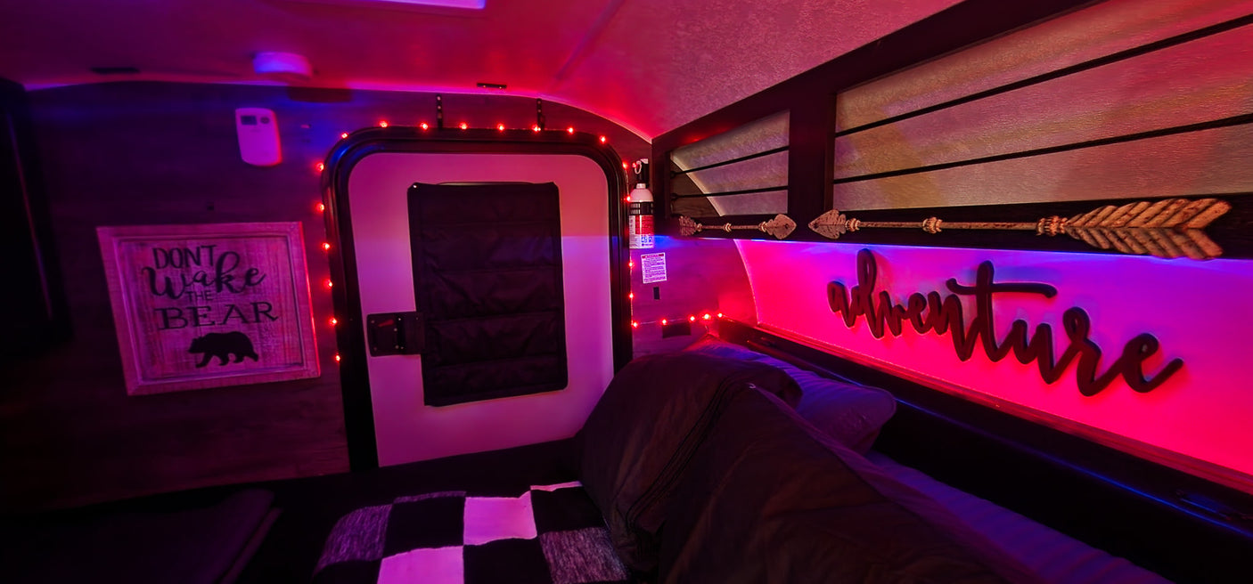 Step into a vibrant RV rental! This cozy interior features red string lights, pink/blue LED ambiance, and adventure decor.