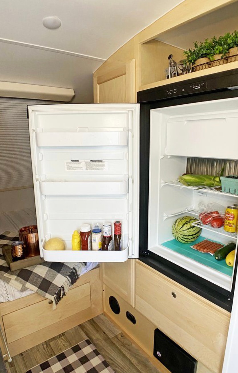 An RV rental kitchen featuring a stocked refrigerator with fresh produce, hot dogs, and condiments for your adventure.
