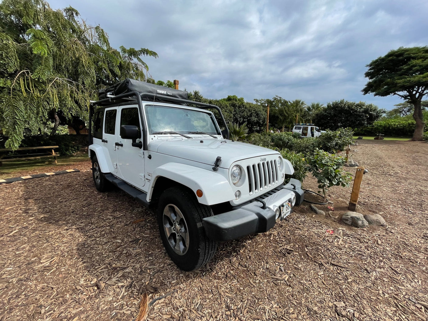 A white Jeep Wrangler with a Thule Tepui rooftop tent, perfect for an adventurous RV rental getaway.