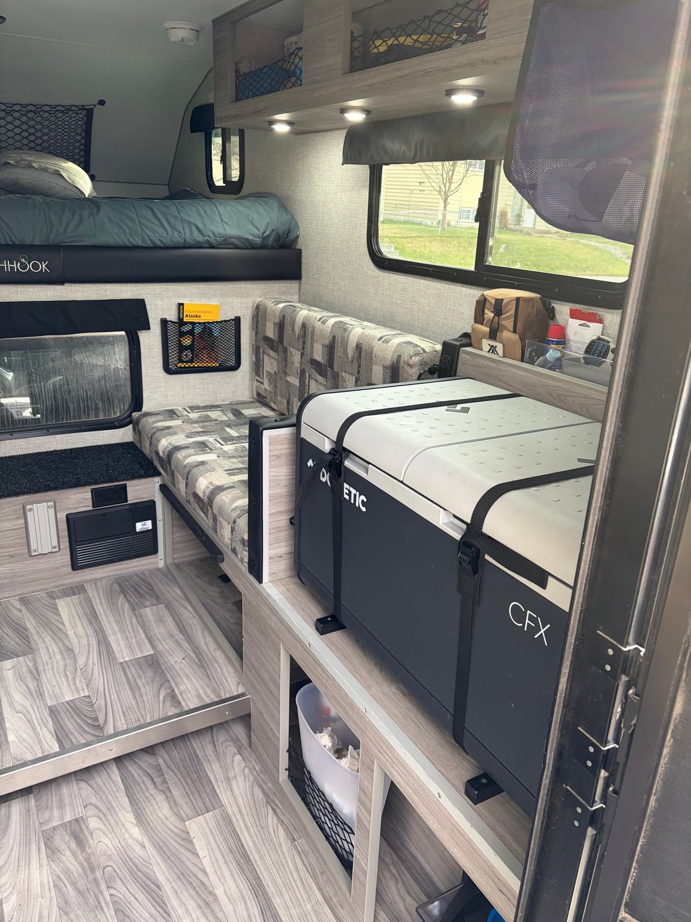 and flooring.|RV rental interior featuring a comfy bed with "FISHHOOK" detail on the frame