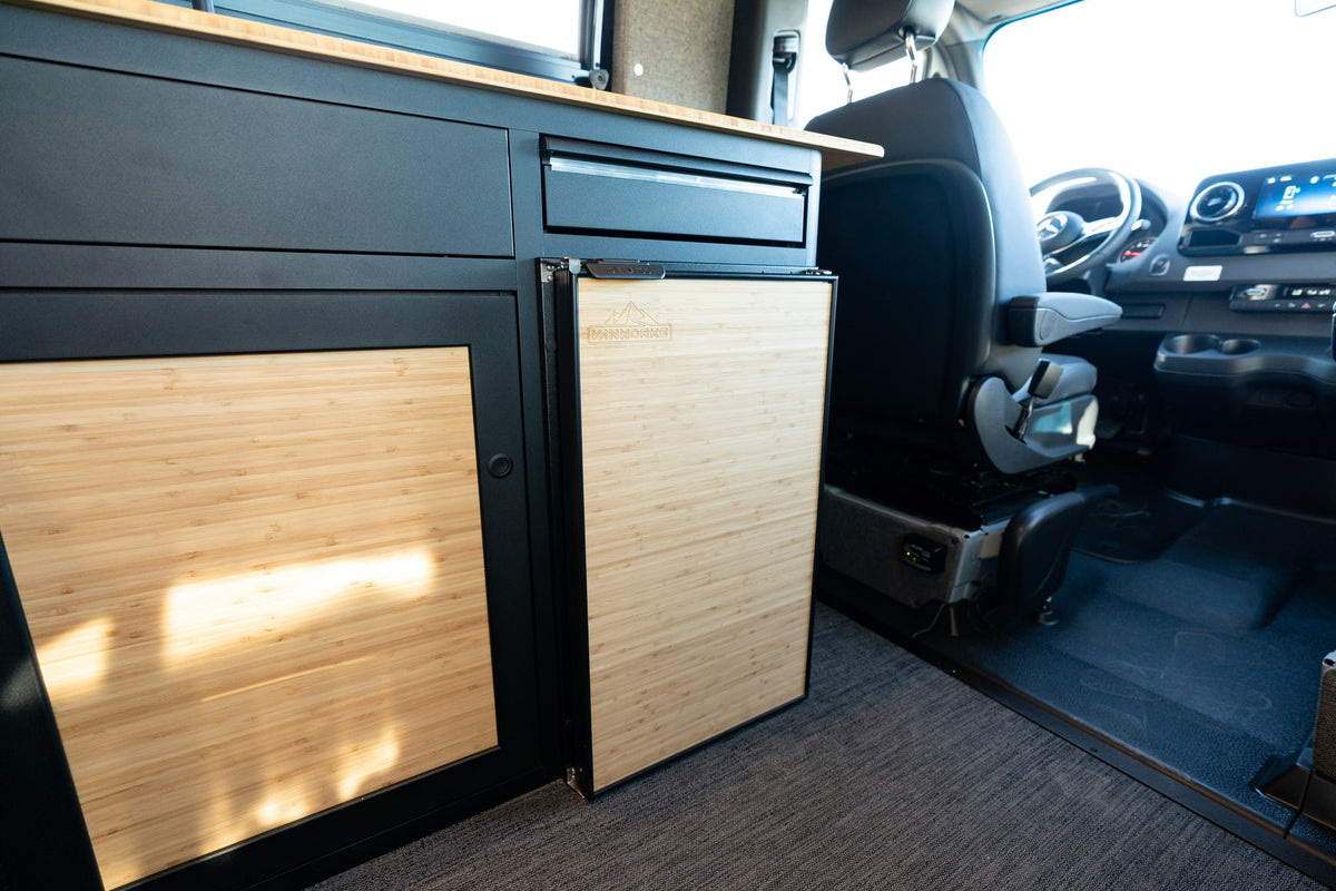 Inside an rv rental, a custom camper van kitchenette with bamboo details, fridge, and Mercedes Sprinter cockpit. — photo 18