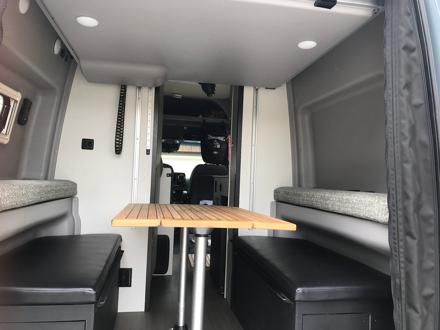 View inside an RV rental: a compact camper van living space with a wooden table & bench seating.