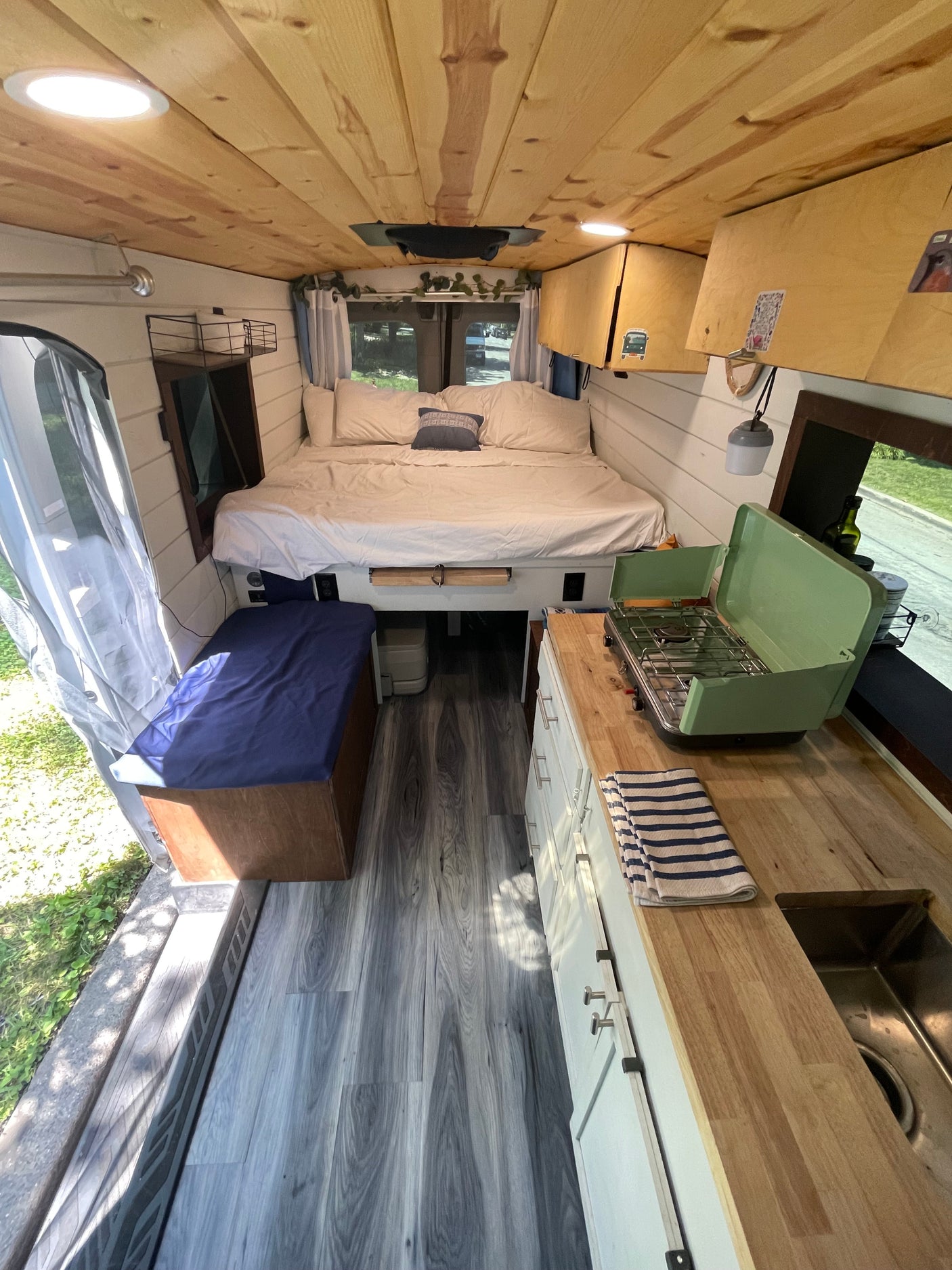 Functional camper van interior of an RV rental, featuring a bed, kitchen, and bench seating.