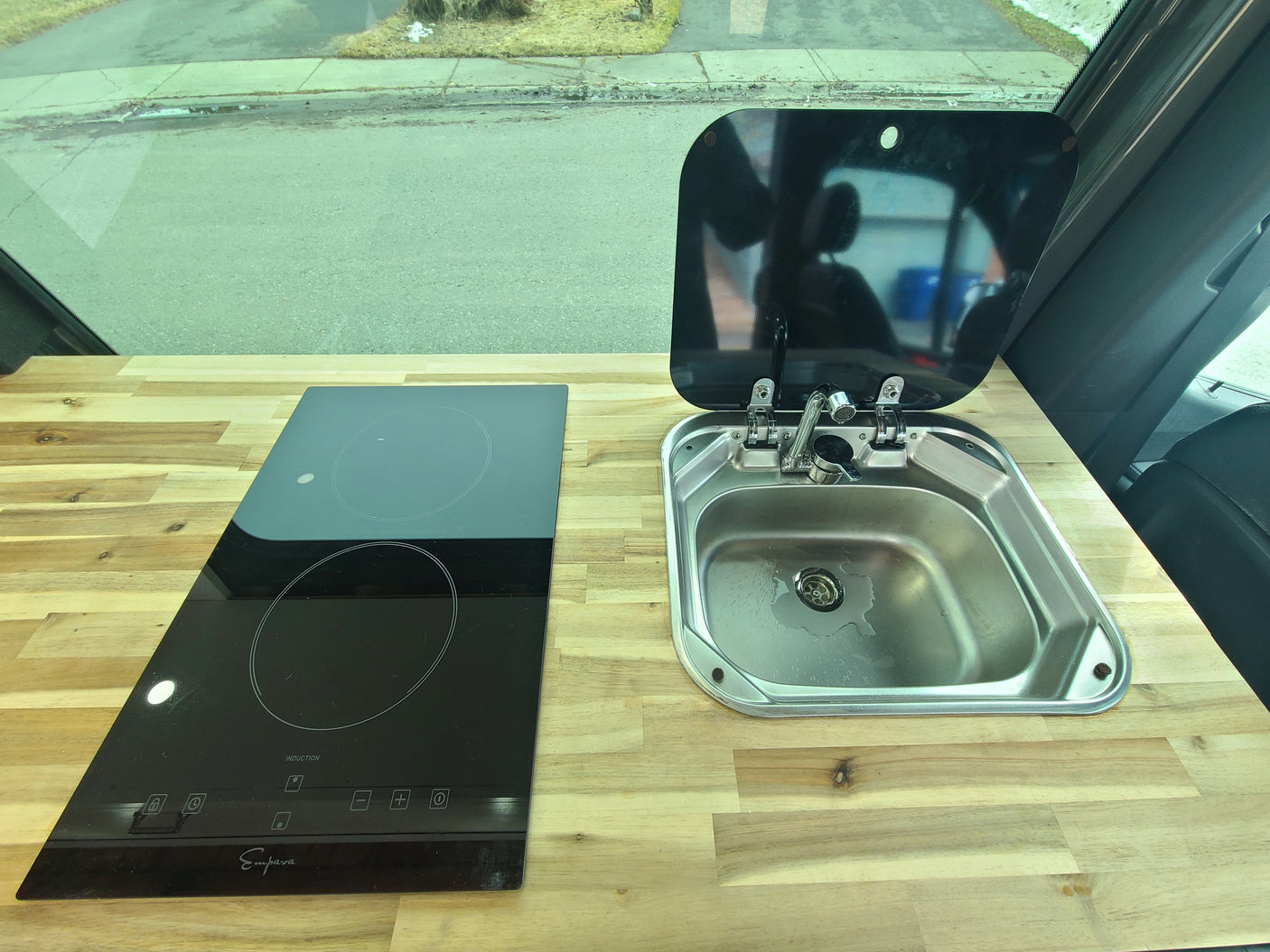 RV rental kitchen showing Empava induction cooktop, stainless steel sink, and wooden countertop for on-the-go cooking.