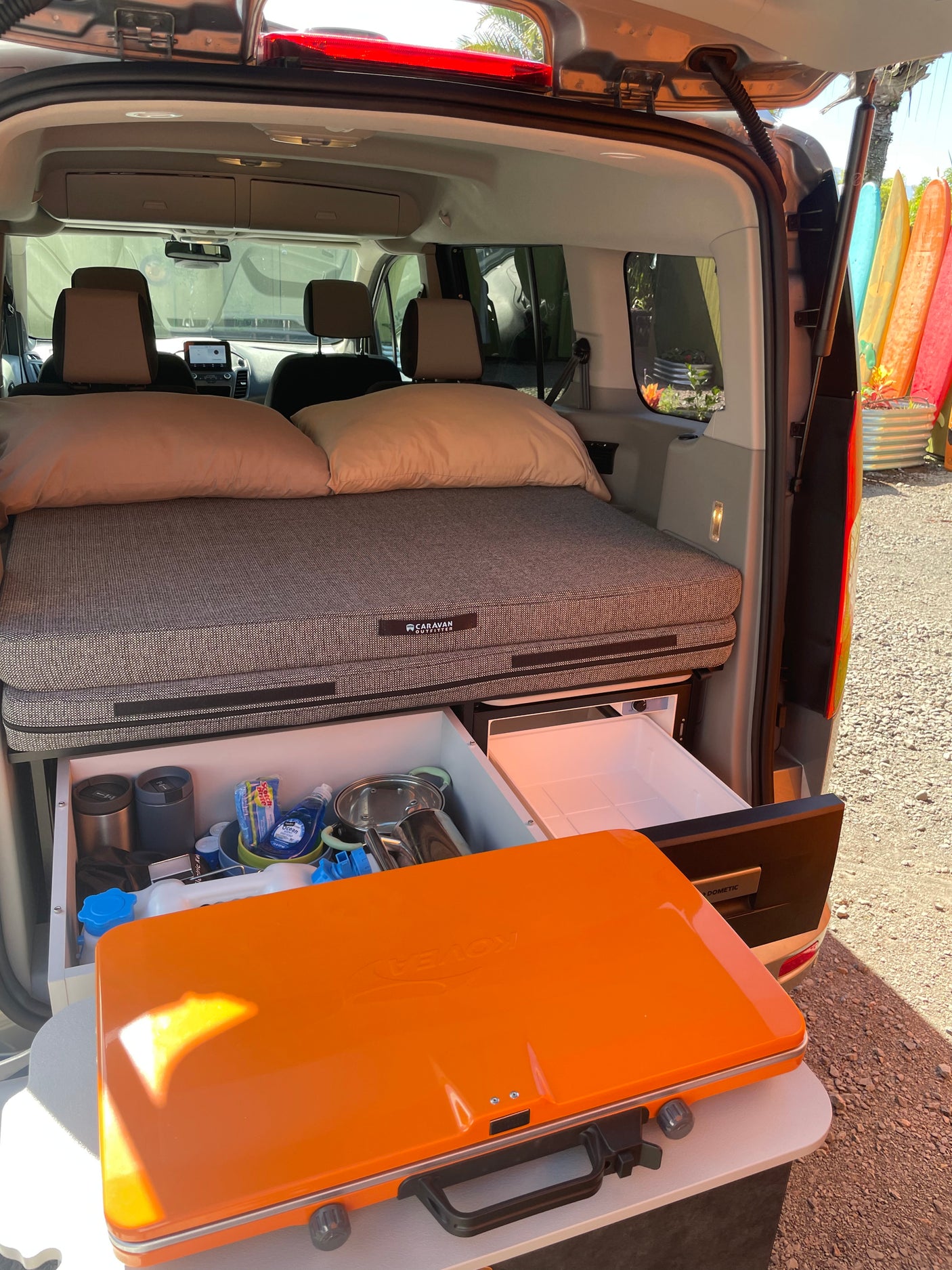 Compact rv rental camper setup features a comfy bed, pull-out kitchen, fridge, and portable stove. Ready for adventure!