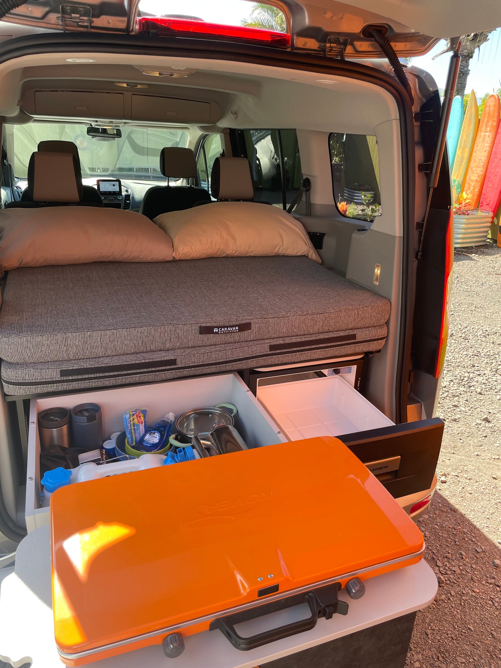Compact rv rental camper setup features a comfy bed, pull-out kitchen, fridge, and portable stove. Ready for adventure!