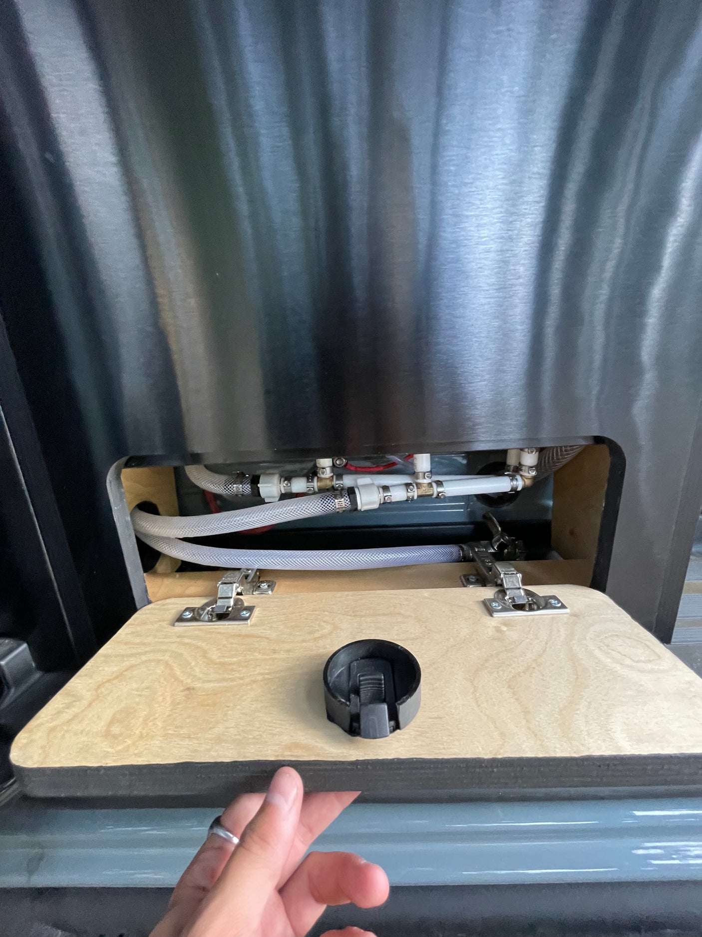 RV rental water system: Hidden plumbing with hoses & connections accessible via a hinged panel.