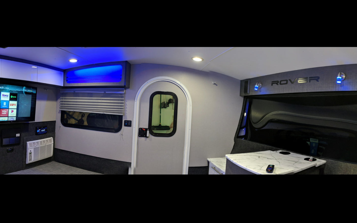 Step inside this modern RV rental! Features include a TV, AC, stylish interior with blue lighting, and a compact design.