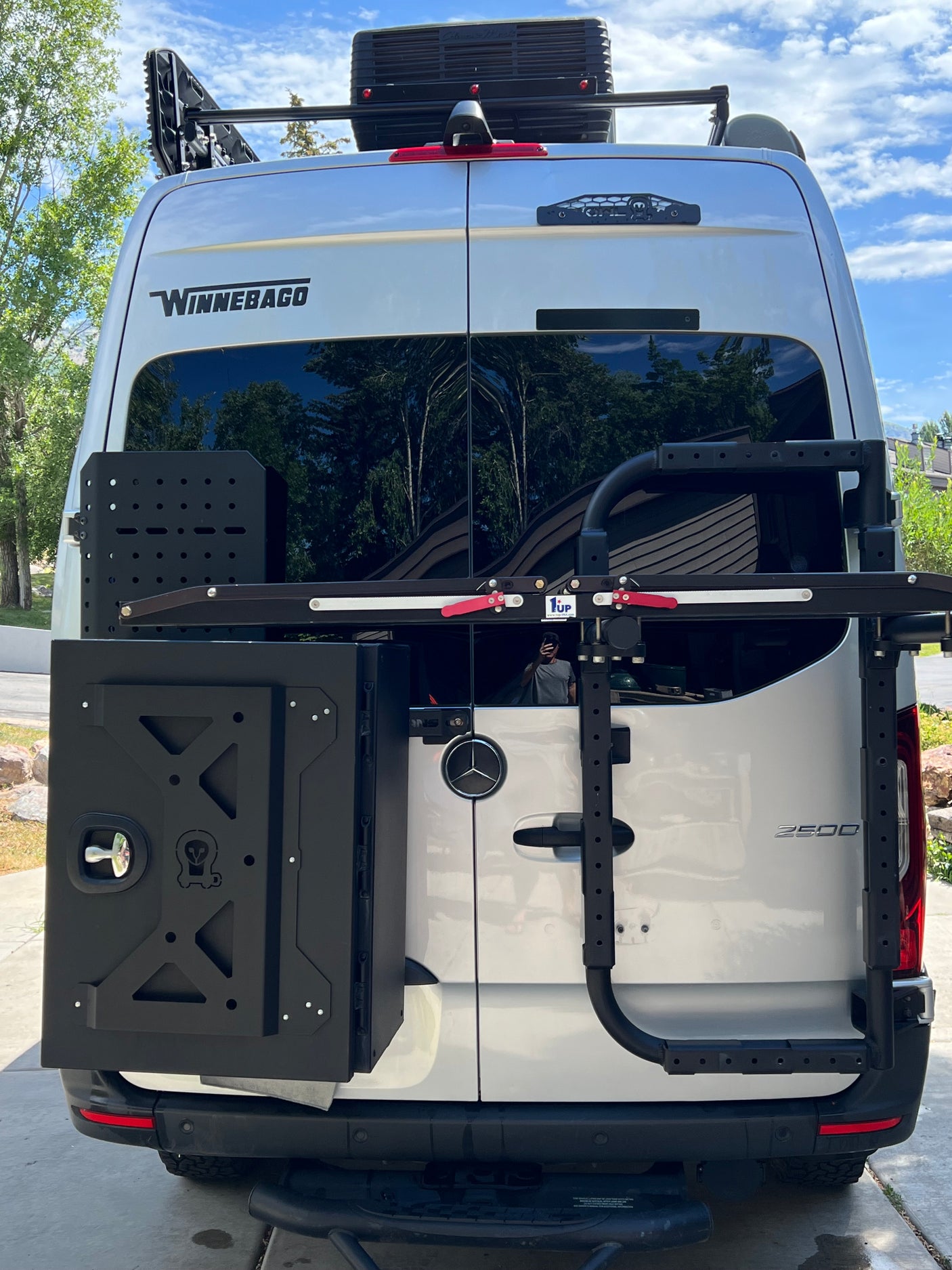 Winnebago camper van RV rental: Rear view showing adventure gear, a storage box, and a bike rack.