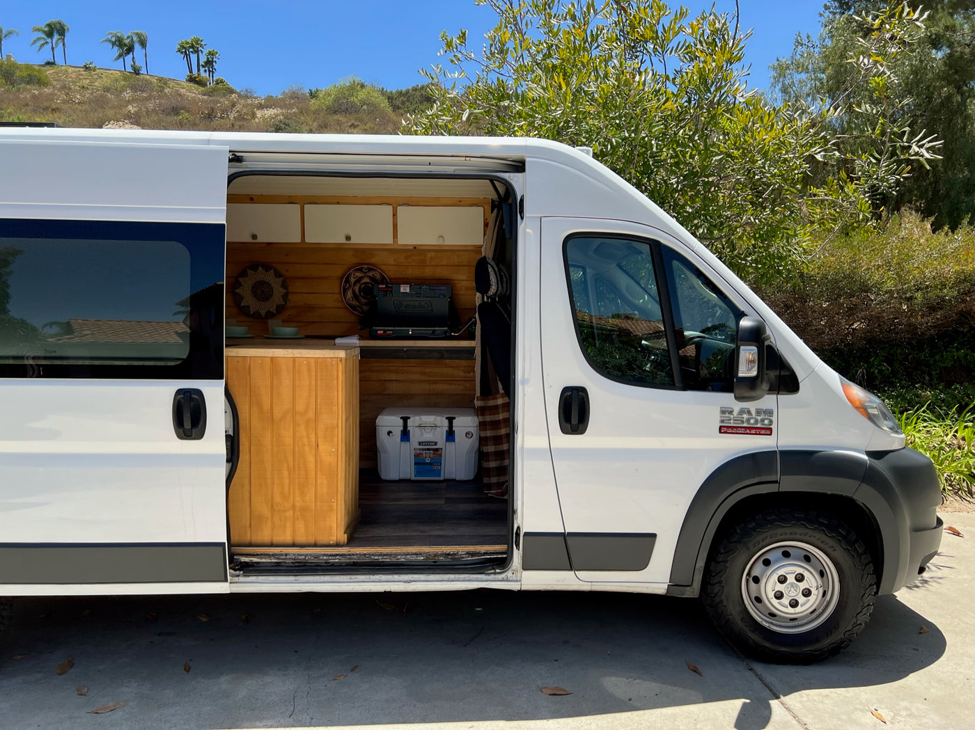 This white Ram ProMaster RV rental, with its side door open, reveals a cozy wooden interior kitchen, ready for adventure. — photo 6