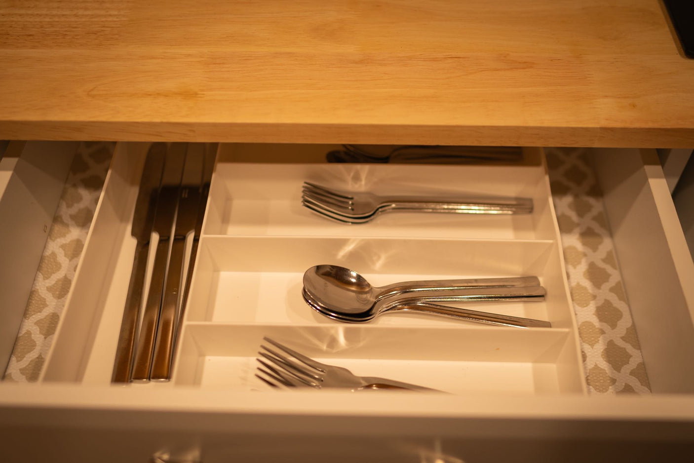 RV rental kitchen drawer open, revealing organized knives, forks, and spoons in a white cutlery tray.
