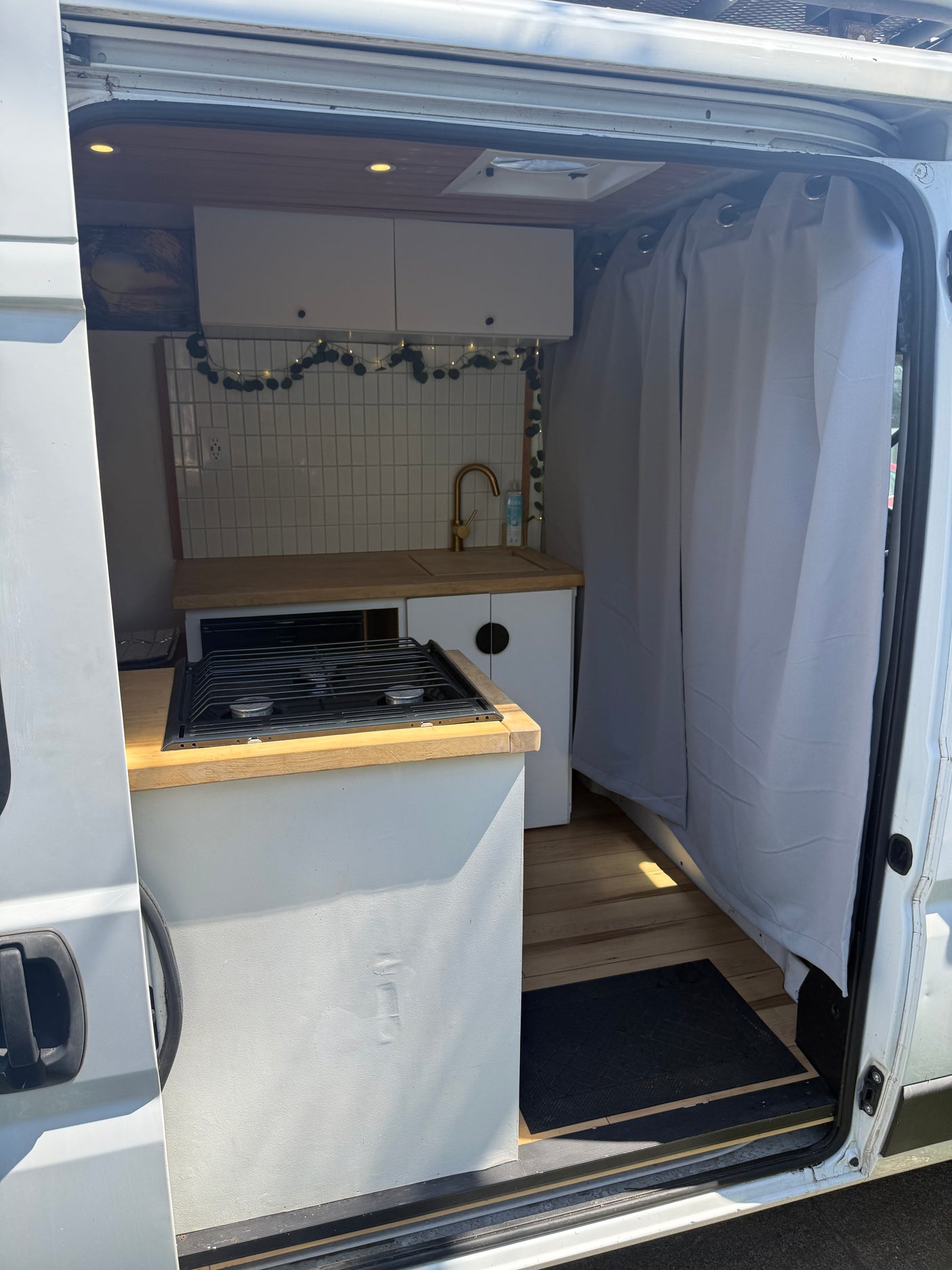 Step into this rv rental camper van: a bright interior featuring a compact kitchen with stove, sink, and charming decor.