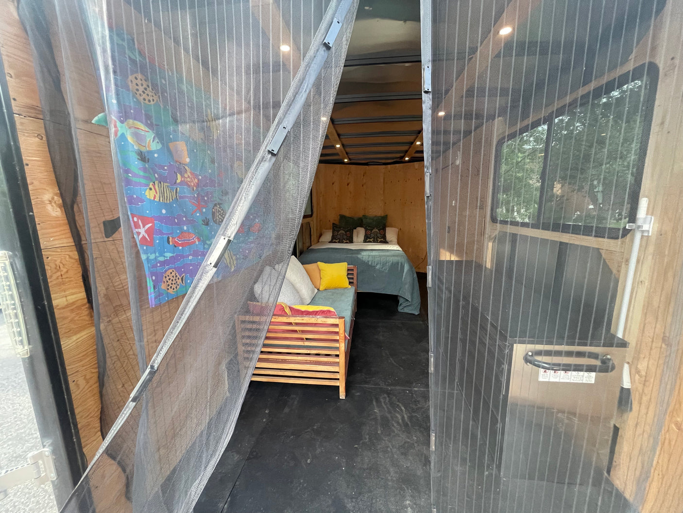 and outdoor views through windows.|Rustic RV rental interior featuring a bed