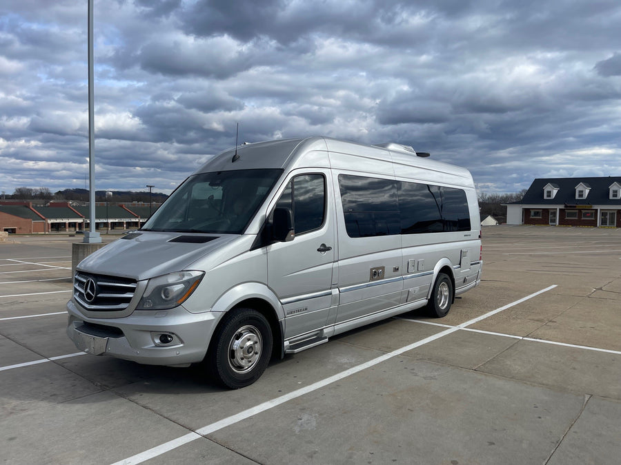 A silver Mercedes-Benz Sprinter Airstream RV rental is parked in a lot under a cloudy sky.|Silver Airstream Interstate luxury RV rental